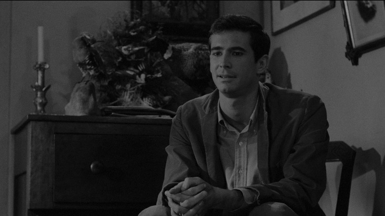 Anthony Perkins as Norman Bates in Psycho, sitting casually in a chair looking over at someone.