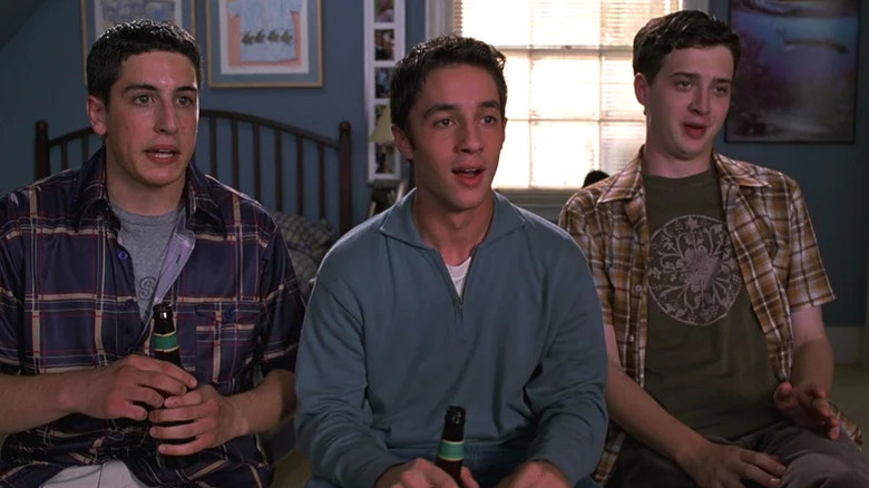 Jim Levenstein (Jason Biggs), Kevin Myers (Thomas Ian Nicholas), and Paul Finch (Eddie Kaye Thomas) sit on a bed in rapt attention holding beers in American Pie