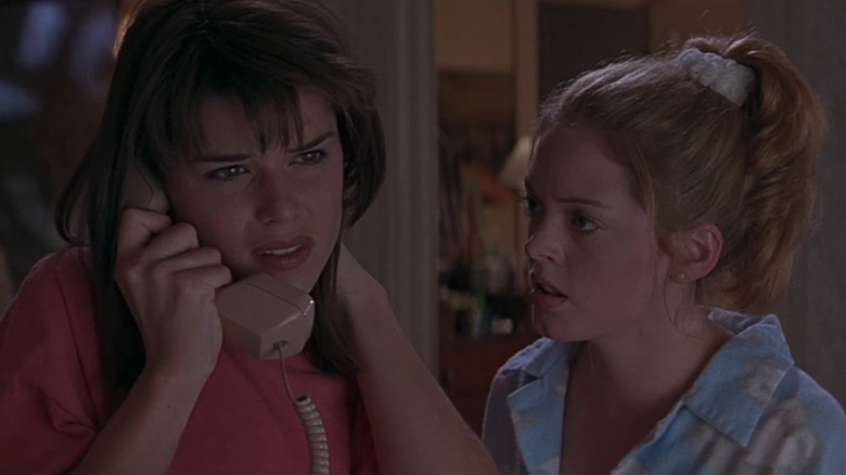 Sidney (Never Campbell) looks scared talking on the phone next to Tatum (Rose McGowan) in Scream (1996)