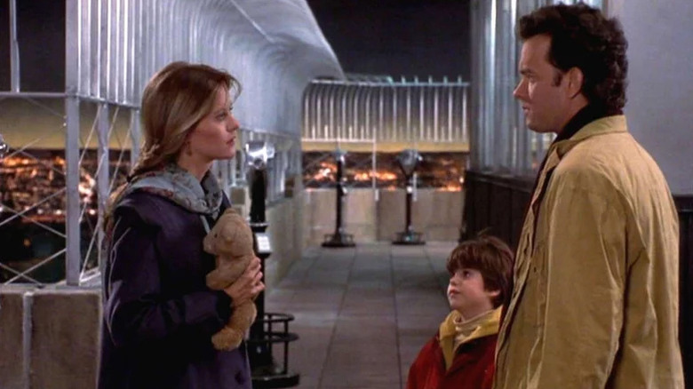 Annie Reed (Meg Ryan) holds a teddy bear facing Sam Baldwin (Tom Hanks) and Jonah Baldwin (Ross Malinger) on the Empire State Building in Sleepless in Seattle