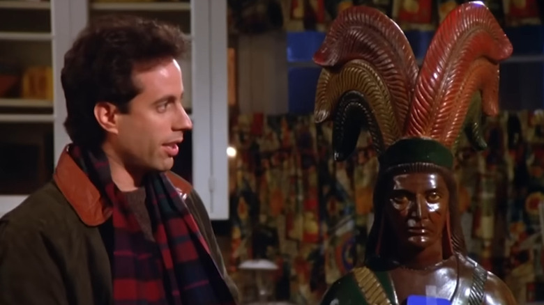 Jerry Seinfeld as Jerry next to a Native American statue in Seinfeld