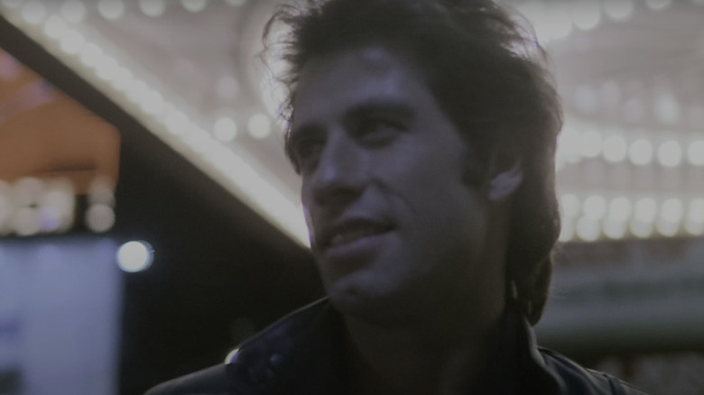 Tony Manero (John Travolta) stands under a lit marquee in Staying Alive