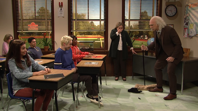 Adam Driver standing over a dead raven while Pete Davidson laughs at a classroom desk