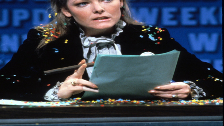 Black-and-white Jane Curtin sitting at the Weekend Update desk at SNL