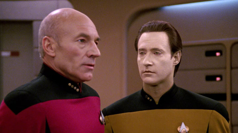 Patrick Stewart as Jean-Luc Picard stands next to Brent Spiner as Data in Star Trek: The Next Generation.