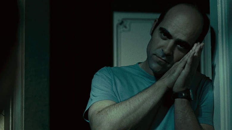 Luis Tosar as César with hands clasped by face miming sleeping motion in Sleep Tight