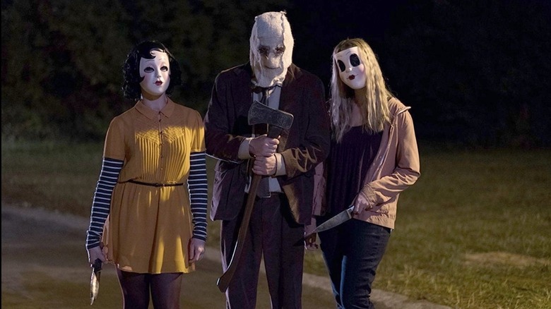 Laura Margolis in yellow dress and pin-up girl mask holding knife, Kip Weeks in brown suit and cloth mask holding axe, and Gemma Ward in doll mask and pink sweatshirt holding knife in The Strangers