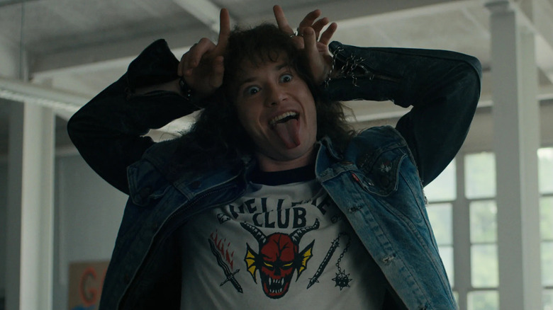 Joseph Quinn as Eddie sticking his tongue out and miming devil horns in Stranger Things 4