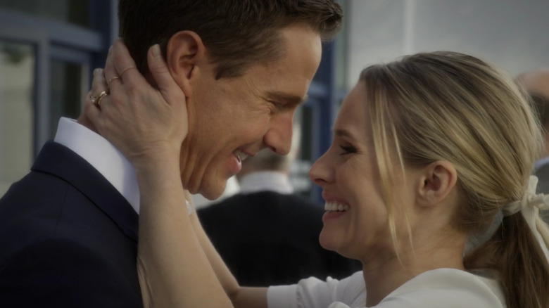 Jason Dohring and Kristen Bell as Logan and Veronica smiling at each other in a wedding in Veronica Mars