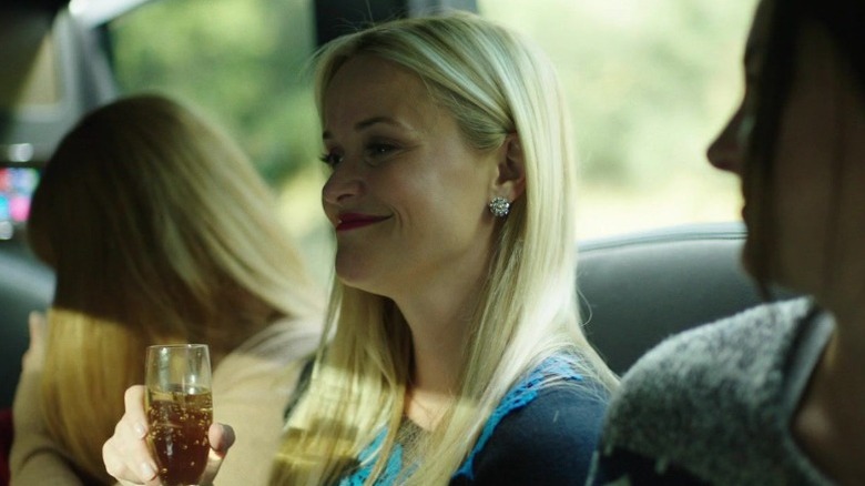 Reese Witherspoon as Madeline Mackenzie sitting in a car while holding a glass of wine and smiling on Big Little Lies