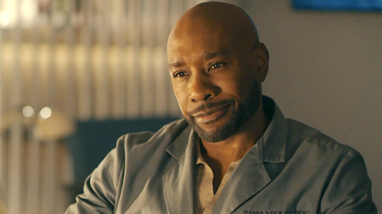 John Watson (Morris Chestnut) smiles sitting in his office in Watson