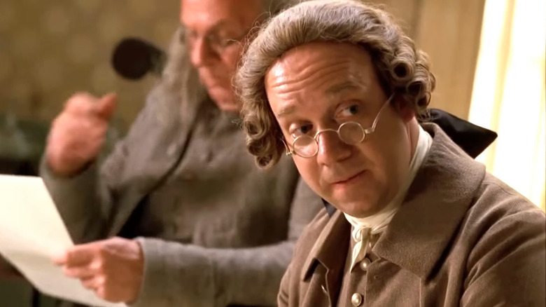 John Adams (Paul Giamatti) looking at colleague over tiny glasses in John Adams