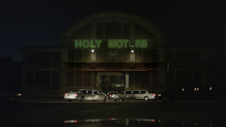 Two limos parked outside Holy Motors garage