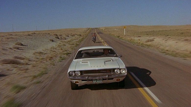 Dodge Challenger driving down highway, motorcycle behind it