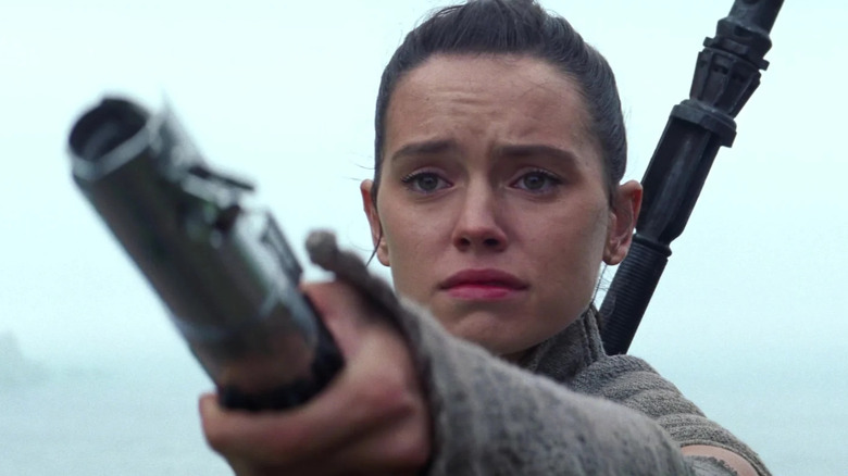 Daisy Ridley as Rey handing the lightsaber to Luke Skywalker at the end of Star Wars: The Force Awakens