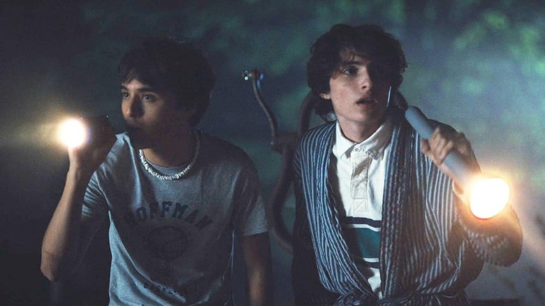 Billy Bryk as Bobby and Finn Wolfhard as Chris holding flashlights in Hell of a Summer