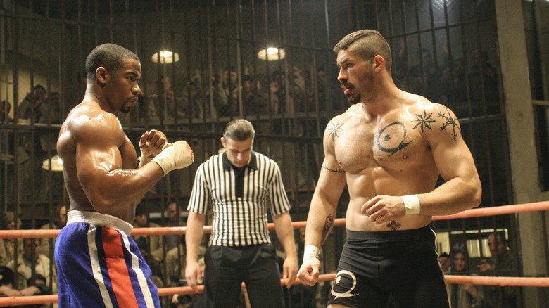 Boxer George Chambers standing in front of Yuri Boyka (Scott Adkins) in front of referee and dozens of prisoners behind bars