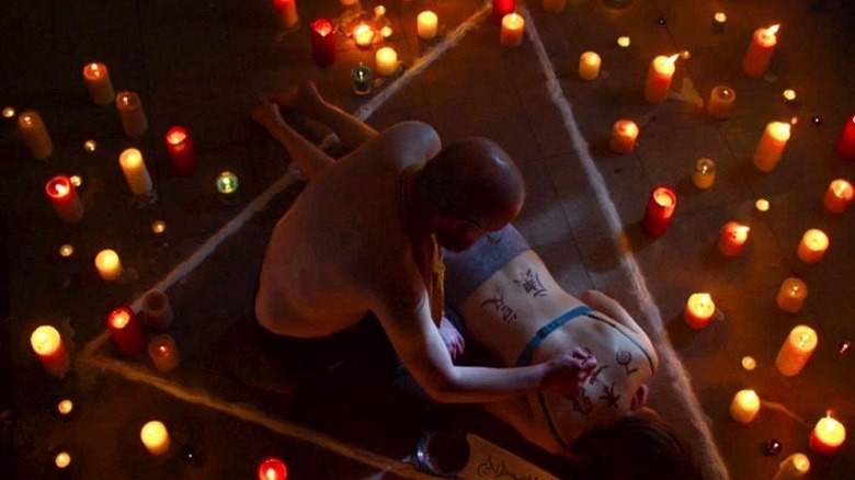 A ritual is underway, the floor covered with candles