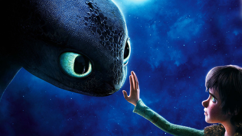 Boy reaches out to touch face of dragon