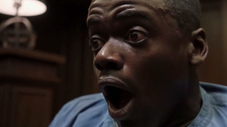 A young man is looking off camera with his eyes wide and mouth stretched into a scream.