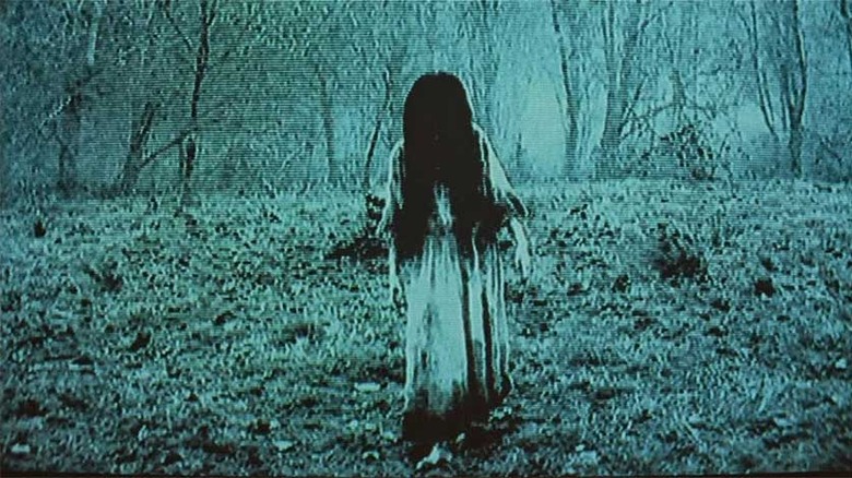 A young girl in a tattered dress and with black hair filmed on camera