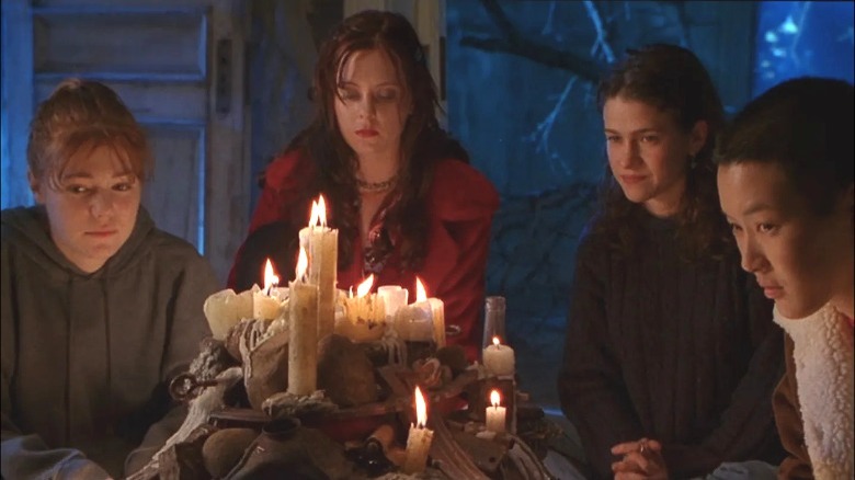 Four teen girls sitting around a pile of candles in Foxfire