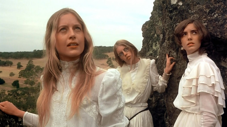 Three girls in white dresses looking up in Picnic at Hanging Rock