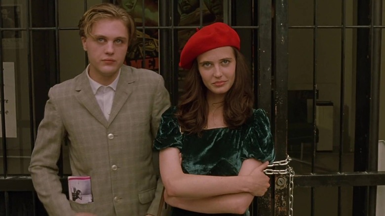 Micheal Pitt standing next to a smirking Eva Green with a red beret in the Dreamers
