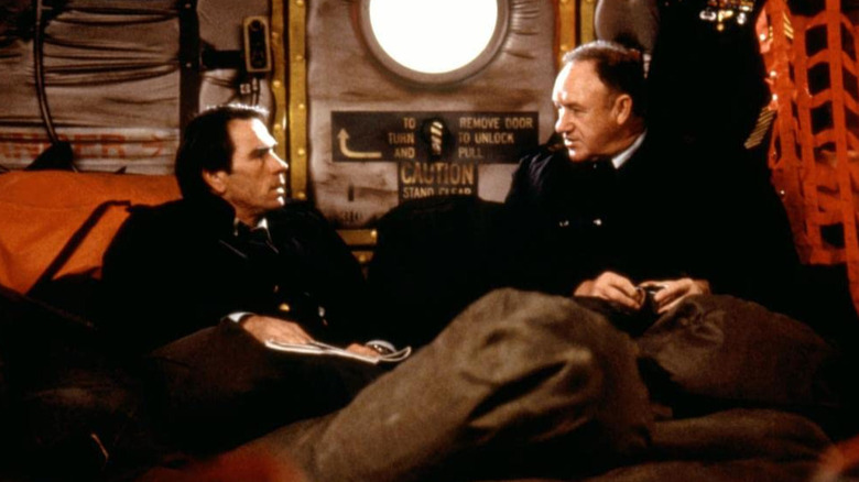 Tommy Lee Jones chatting with Gene Hackman on a troop transport plane