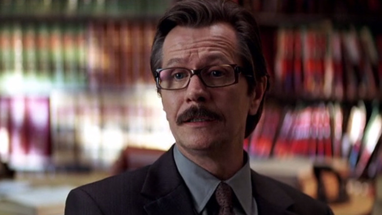 Jim Gordon (Gary Oldman) sits in Harvey Dent's office in The Dark Knight