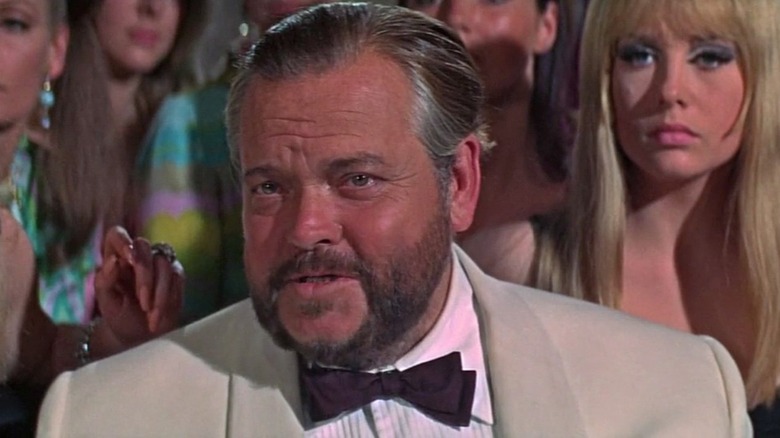 Le Chiffre (Orson Welles) jeers while surrounded by beautiful women in Casino Royale (1967)