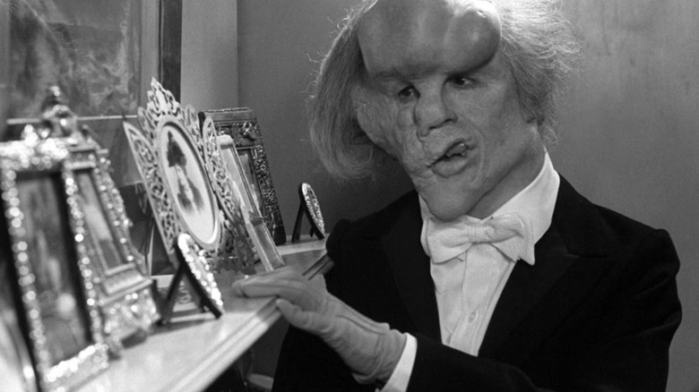 John Hurt as John Merrick looking at photos in The Elephant Man