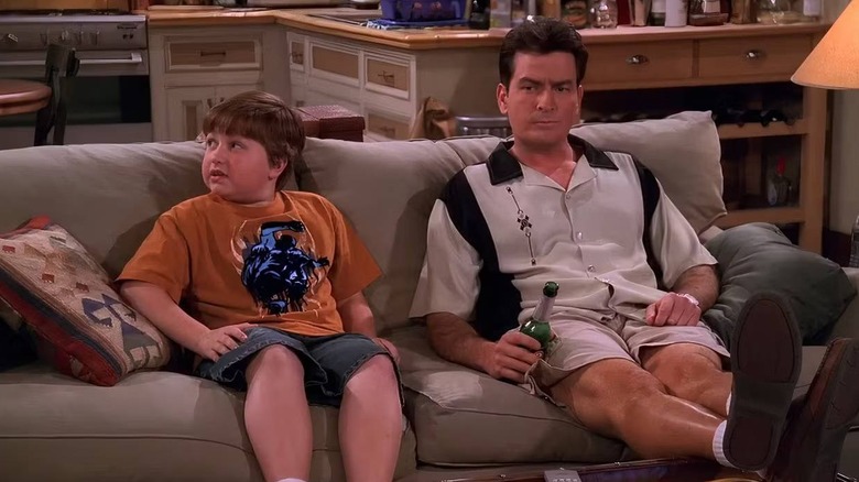 Jake Harper (Angus T. Jones) sitting with Charlie Harper (Charlie Sheen) on Two and a Half Men