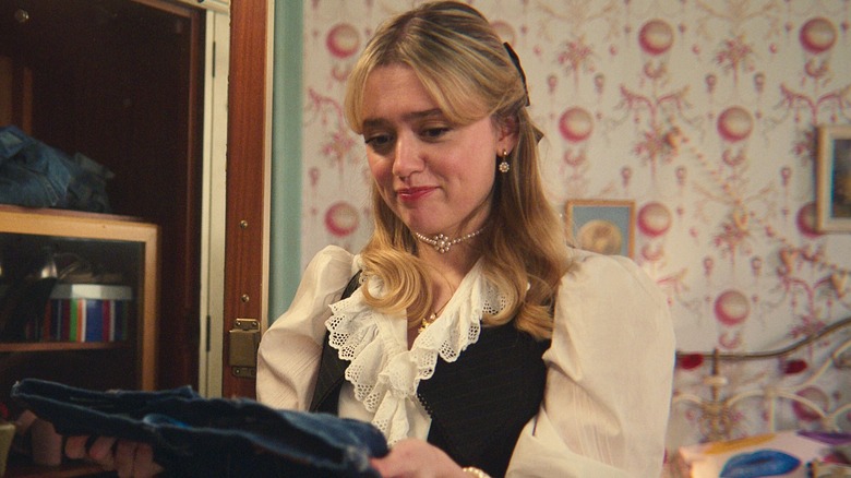 Aimee Lou Wood as Aimee looking at a pair of jeans in Sex Education