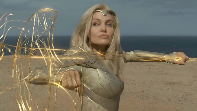 Angelina Jolie as Thena standing with an energetic spear and shield in Eternals