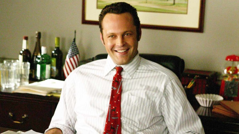 Vince Vaughn as Jeremy Grey smiles behind a desk in Wedding Crashers