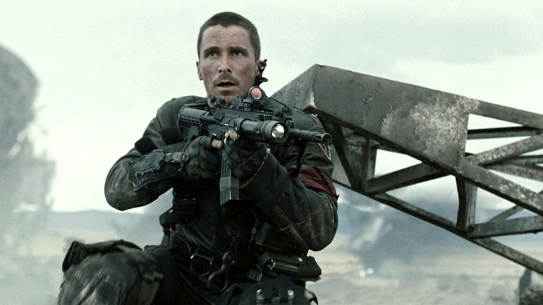Christian Bale as John Connor standing with a gun in a post-apocalyptic settin in Terminator Salvation