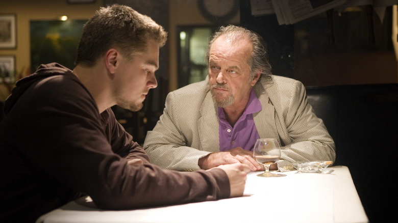 Leonardo DiCaprio as William Costigan Jr. sitting at a table in a restaurant next to Jack Nicholson as Frank Costello who is staring at him in The Departed