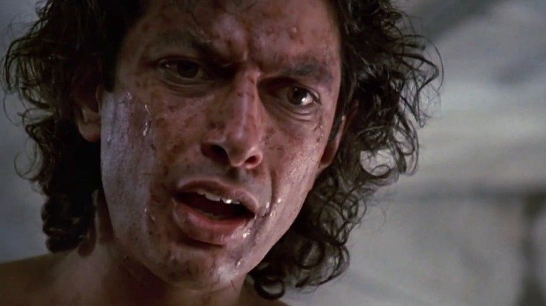 Jeff Goldblum as Seth Brundle looking shocked with scars on his face in The Fly