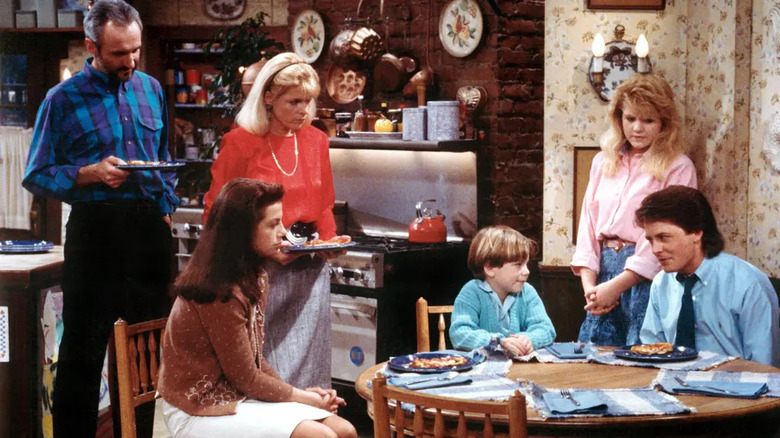 Michael Gross, Justine Bateman, Meredith Baxter, Brian Bonsall, Tina Yothers, and Michael J. Fox as Steven, Mallory, Elyse, Andy, Jennifer, and Alex Keaton gather around the kitchen table in Family Ties