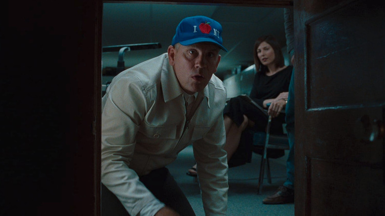 John Malkovich peeks into a tiny door  that goes into his head as Maxine Lund (Catherine Keener) looks on in Being John Malkovich