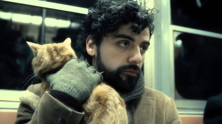Oscar Isaac as Llewyn Davis holding a cat on the subway in Inside Llewyn Davis
