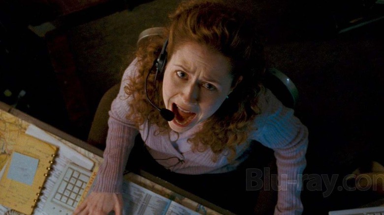Jenna Fischer as Shelby Cunningham in Slither, sitting at her computer with a headset on, looking directly up as the camera looks down at her while she screams.