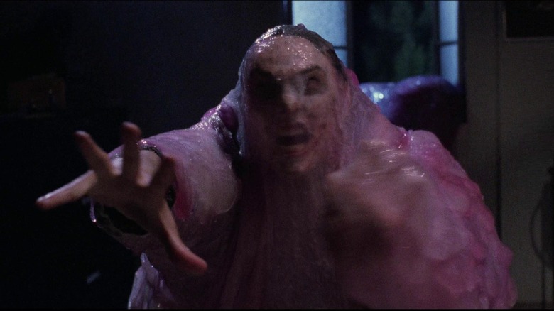 Donovan Leitch as Paul Taylor in The Blob, reaching his hands out with his face in a grimace through a covering of blob goo.