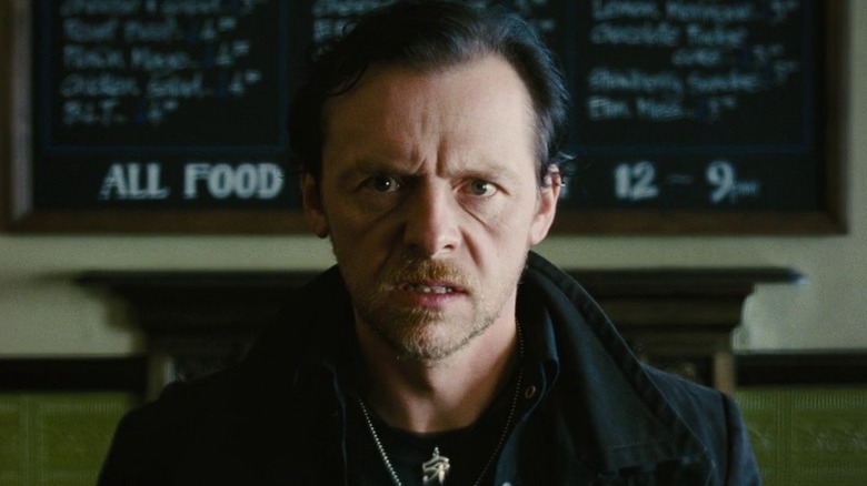Simon Pegg as Gary King in The World's End, centered and sitting in front of a pub menu as he looks straight past the barrel of the lens, looking appalled.