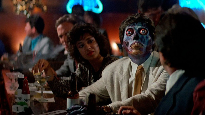 One of the exposed aliens in They Live, sitting at a bar surrounded by people who don't seem to be paying him all that much mind.