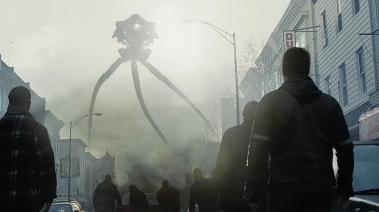 Tom Cruise as Ray Ferrier in War of the Worlds, standing in a city street and looking up at the monstrous tripod towering over the town.