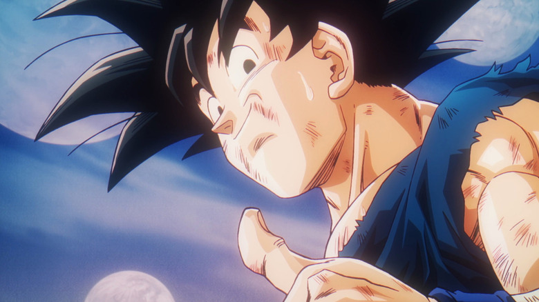 A bruised and sweaty Goku smiles downward and gives a thumbs up in Dragon Ball Z