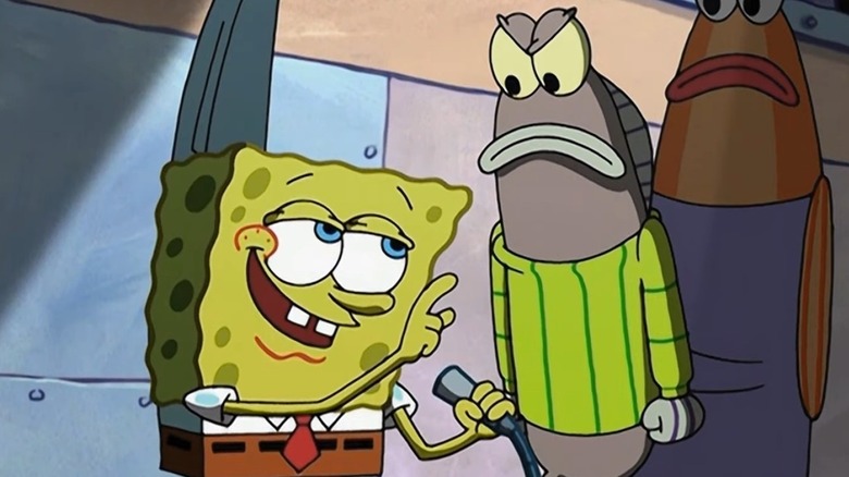 SpongeBob SquarePants (Tom Kenny) confidently speaks into a mic in a spotlight next to angry fish in SpongeBob SquarePants