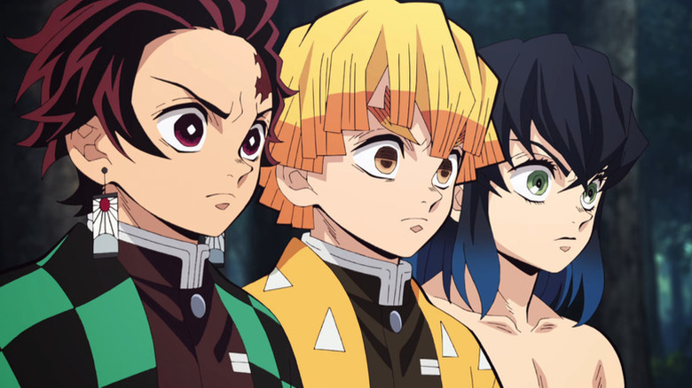 Tanjiro Kamado stands sternly in a row with Zenitsu Agatsuma and Inosuke Hashibira in Demon Slayer: Kimetsu no Yaiba